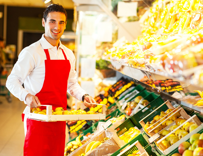 Grocery store worker carrying fruit on a tray in the produce section