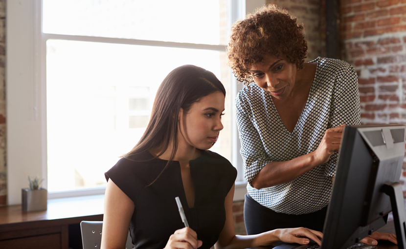 Youth and adult discussion in an office with computer