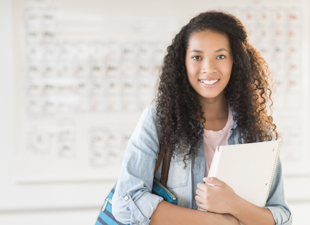 Youth smiling and standing in front of a periodic table