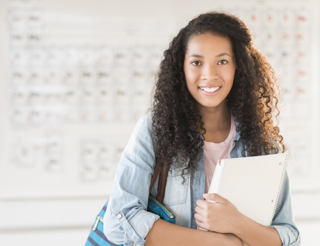 Youth smiling and standing in front of a periodic table