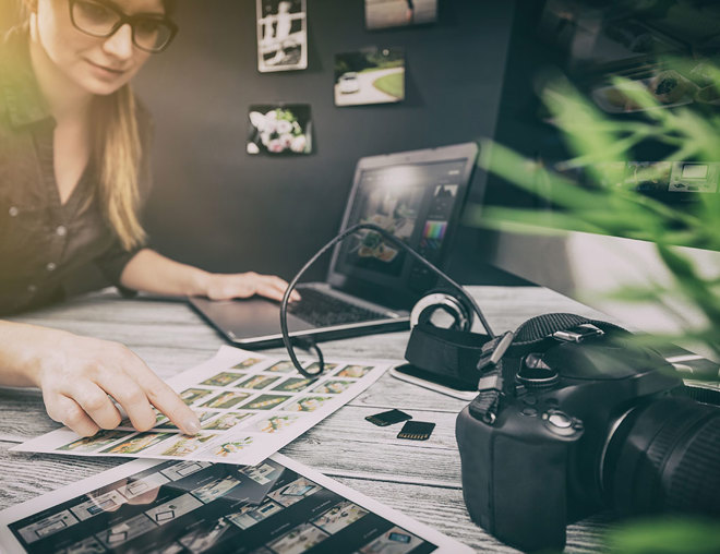 Person reviewing photographic proofs with laptop and DSLR camera