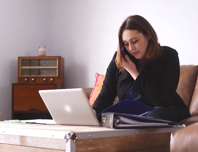 Job seeker on a couch talking on the phone and looking at a laptop