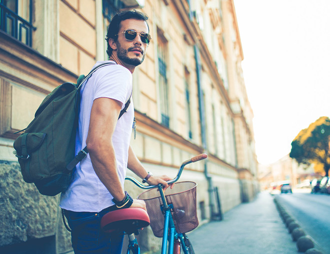 Student walking a bike on a city sidewalk
