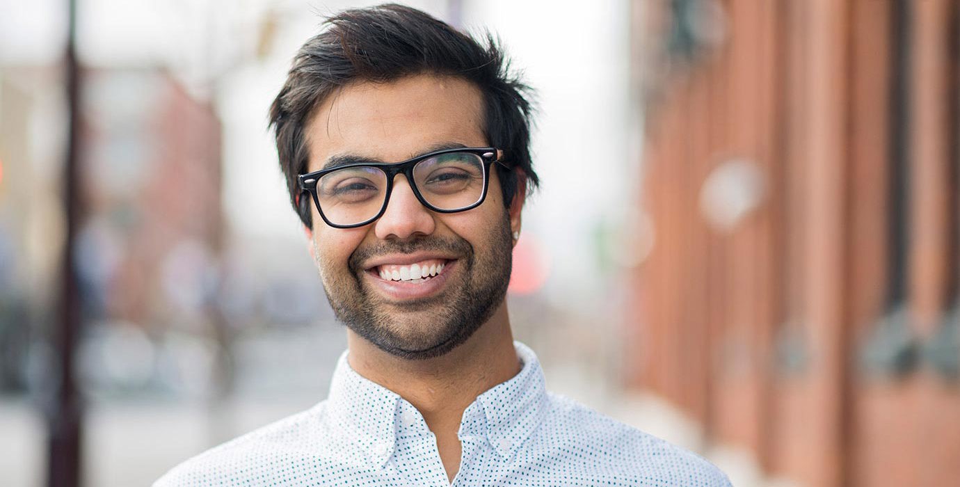Smiling young man in collared shirt and glasses.