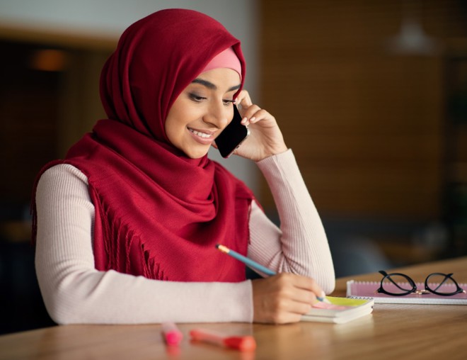 Person speaking on phone and taking notes.