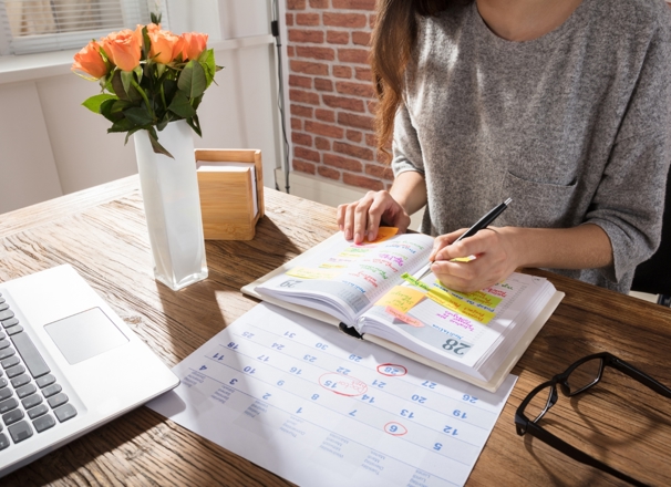 Person filling out weekly schedule on a calendar.
