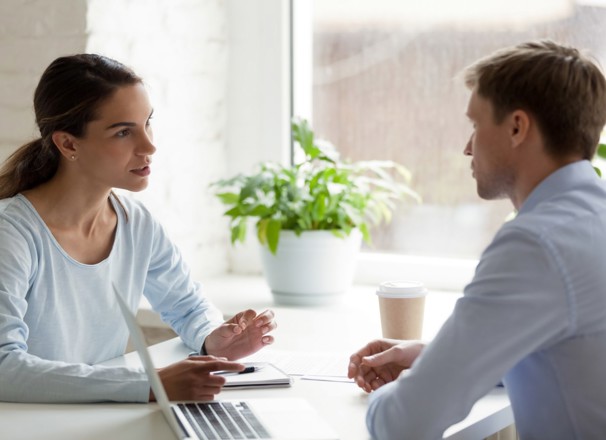 Coworkers talking at a table in the office.