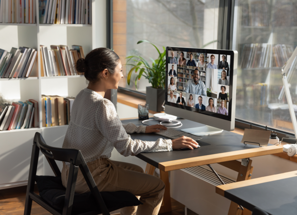 Person video conferencing with a group of people from desktop computer.