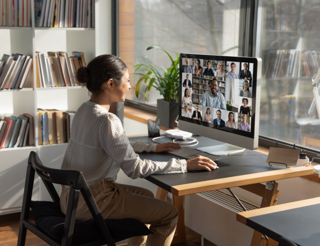 Person video conferencing with a group of people from desktop computer.
