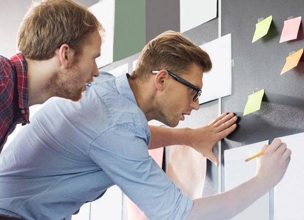 2 people writing on pieces of paper stuck to the wall
