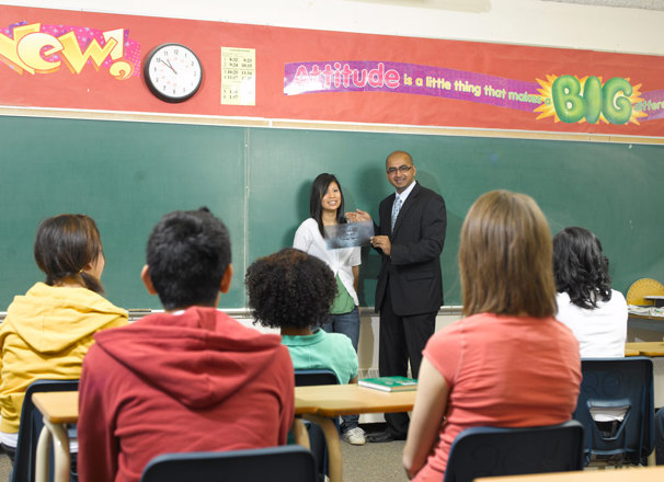 2 teachers standing in front of a classroom of youth