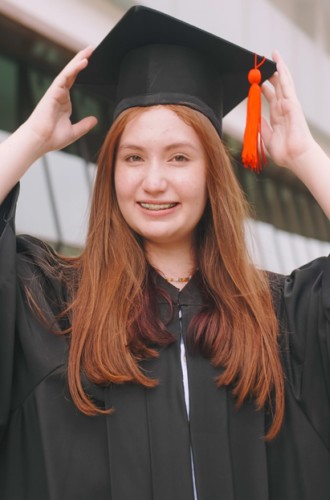High school student posing for graduation photo in cap and gown.