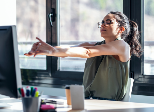Office worker leaning back from computer and stretching arms.