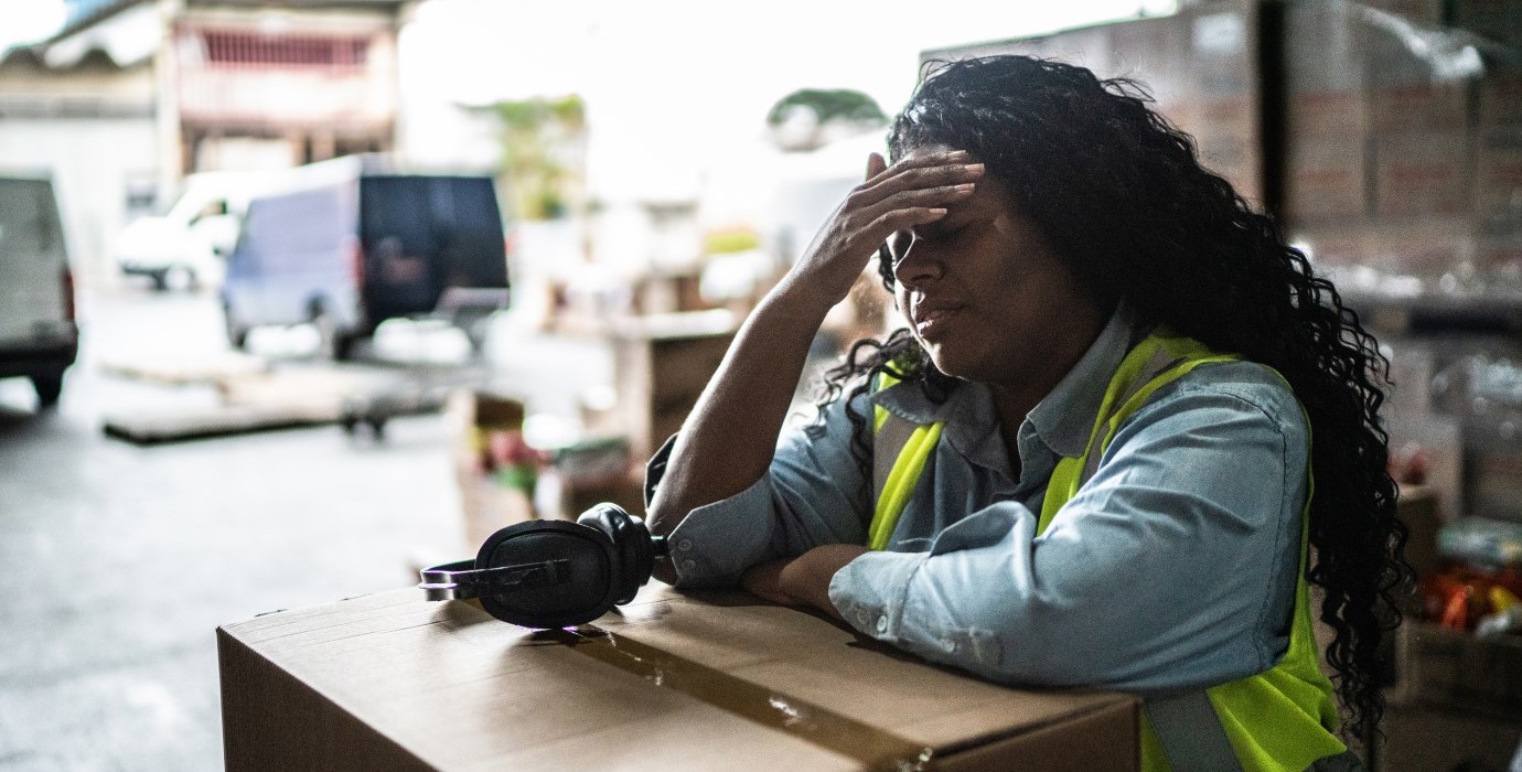 Tired warehouse worker leaning on a box.