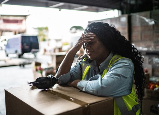 Tired warehouse worker leaning on a box.
