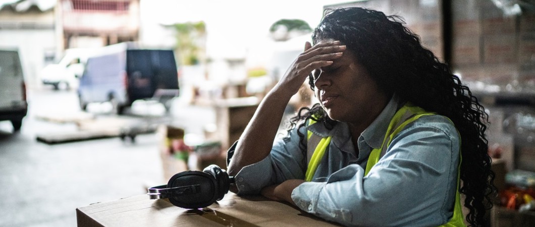 Tired warehouse worker leaning on a box.