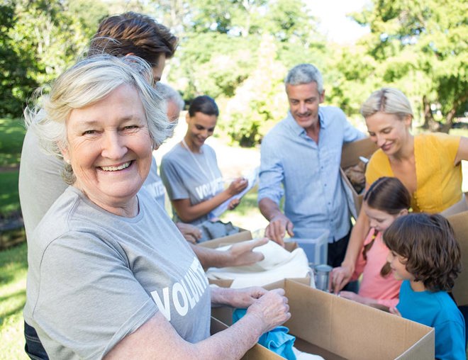 Volunteer smiling at the camera while working with other volunteers in a park