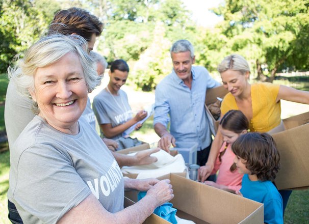 Volunteer smiling at the camera while working with other volunteers in a park