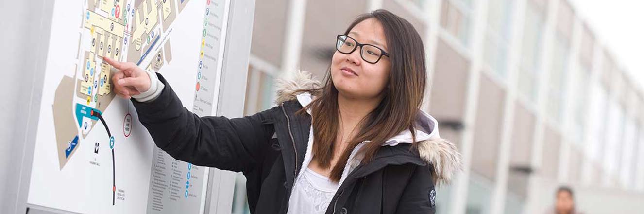 Student on campus pointing to a school map