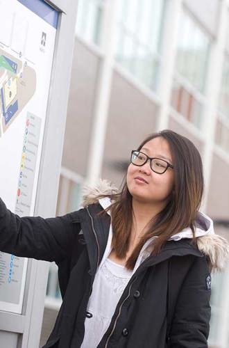 Student on campus pointing to a school map