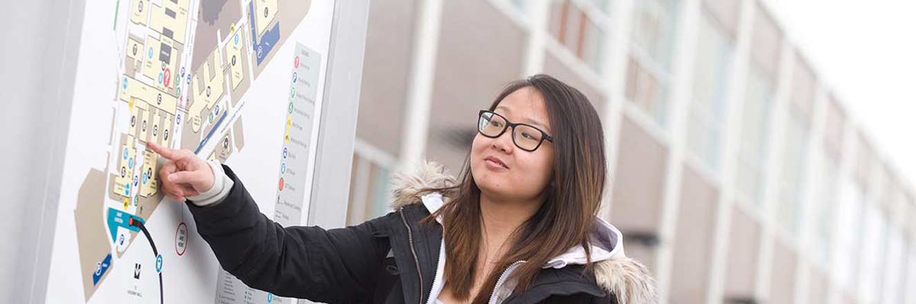 Student on campus pointing to a school map