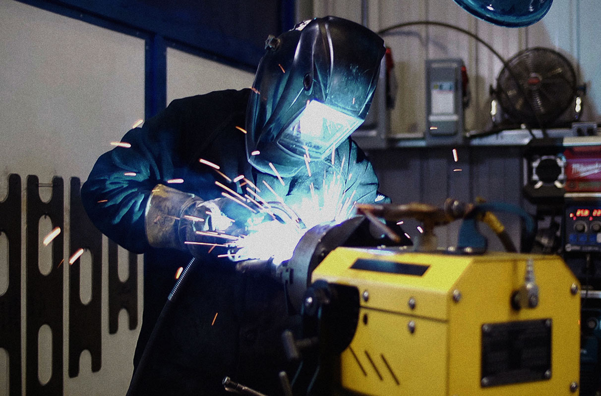 Worker with helmet down welding in a shop