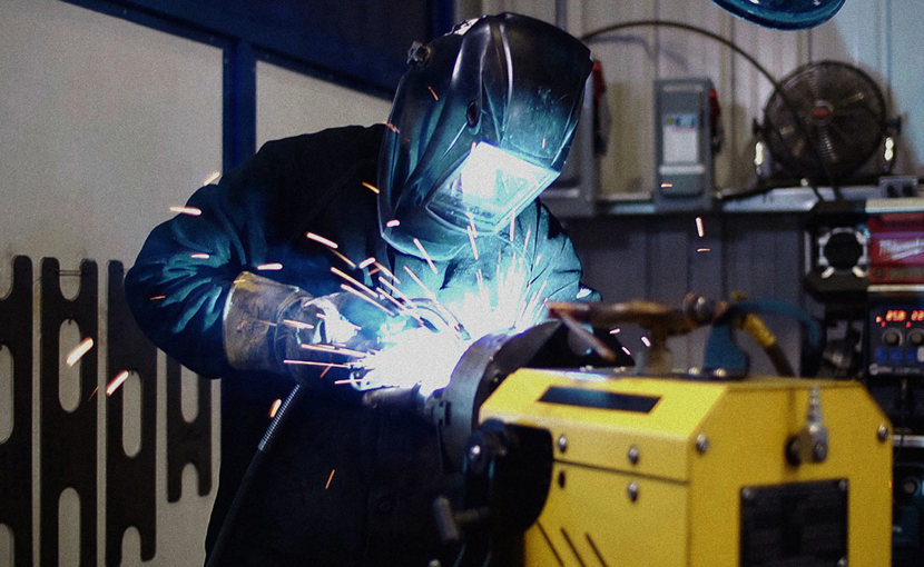Worker with helmet down welding in a shop