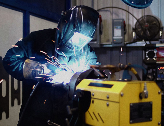 Worker with helmet down welding in a shop
