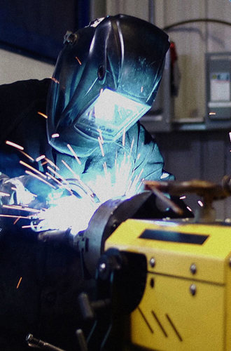 Worker with helmet down welding in a shop