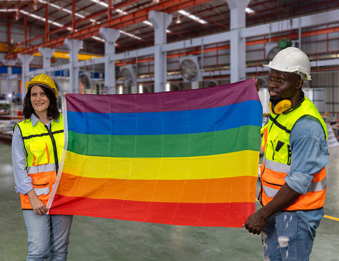 2 employees holding gay pride flag in factory