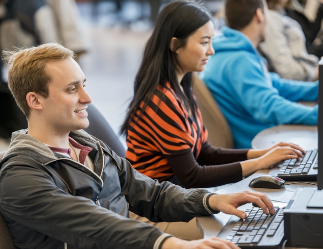 Student typing on a keyboard in a computer lab.