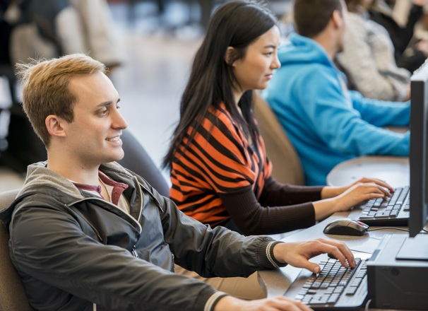 Student typing on a keyboard in a computer lab.