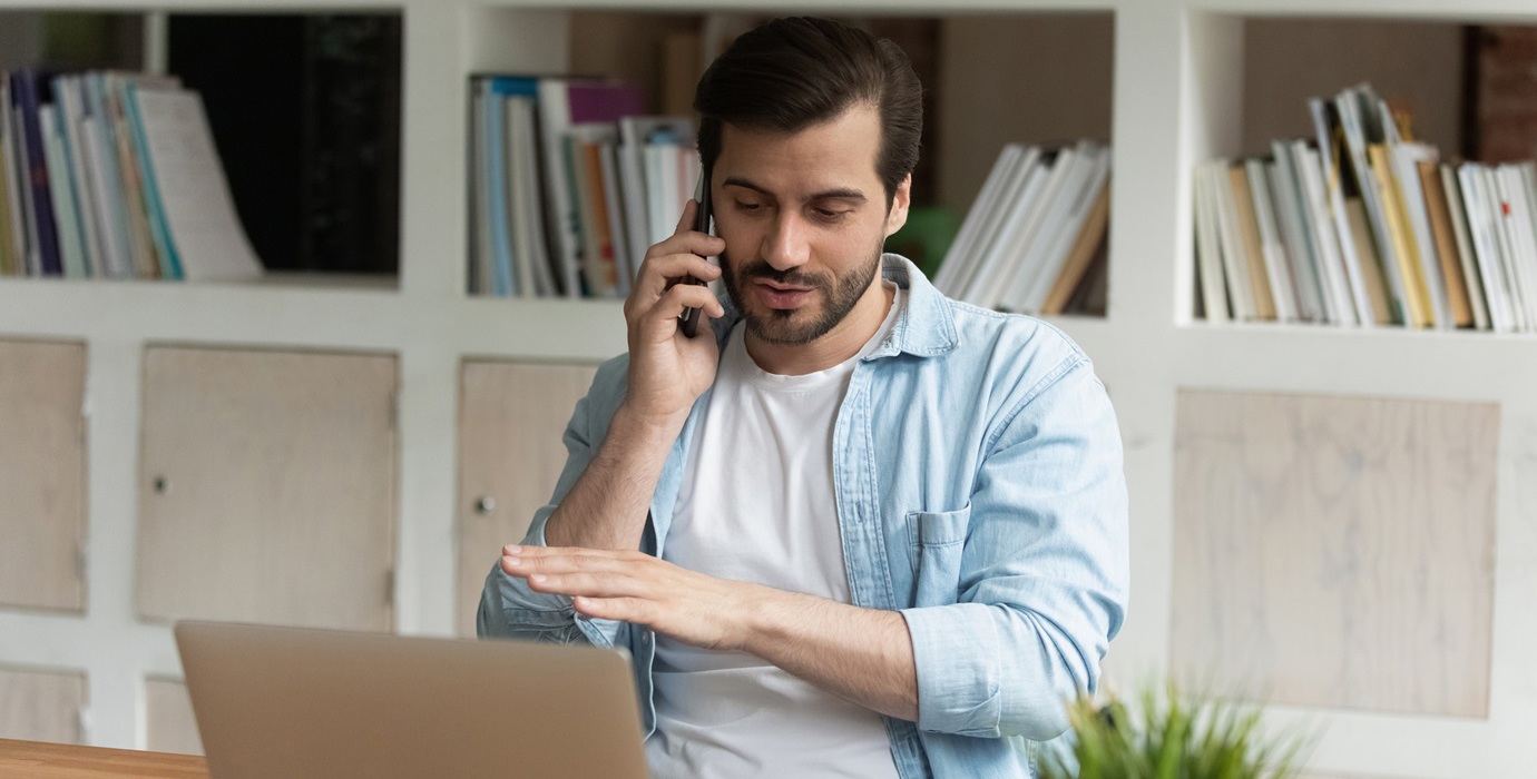 Person talking on phone while sitting at desk. 
