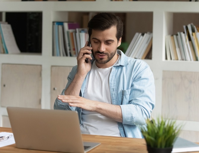 Person talking on phone while sitting at desk. 