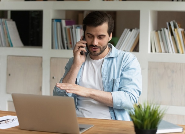 Person talking on phone while sitting at desk. 