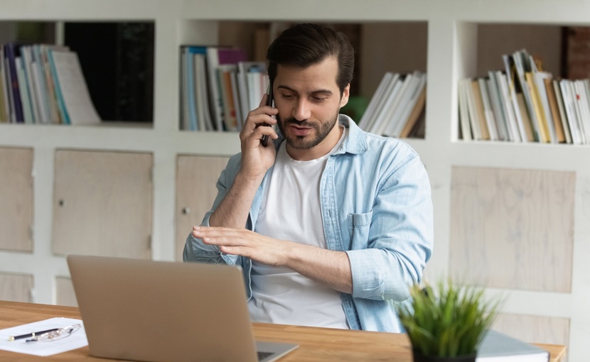 Person talking on phone while sitting at desk. 