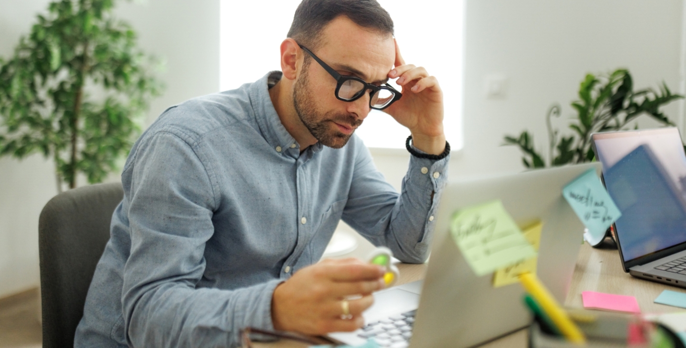 Worker at desk using a fidget spinner while looking at laptop. 