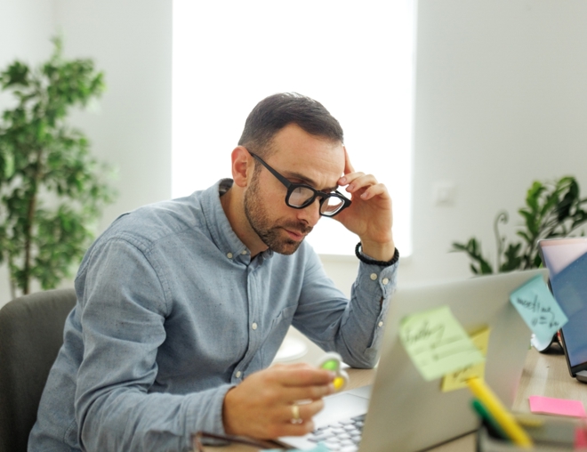 Worker at desk using a fidget spinner while looking at laptop.