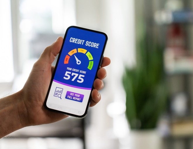 Hand holding a phone that has a credit score rating system on the screen.