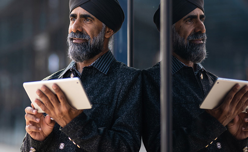 A mature person uses technology to manage tasks, standing in an urban business area.