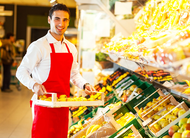 Grocery store worker carrying fruit on a tray in the produce section
