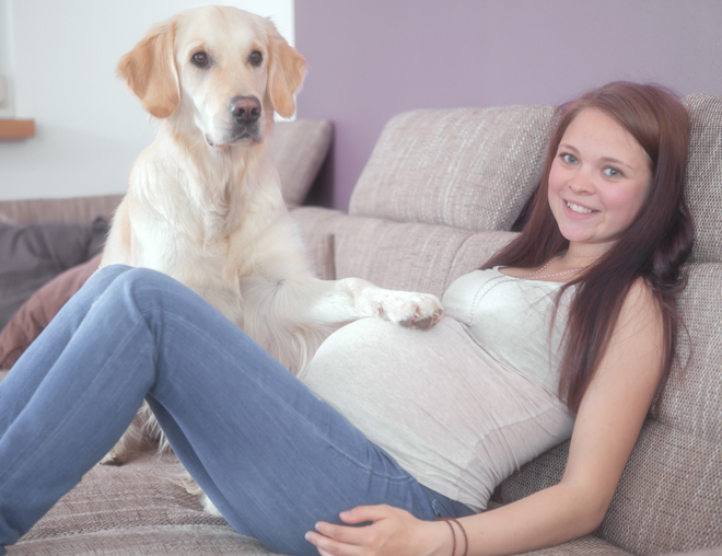 Pregnant youth reclining on sofa with dog