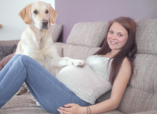 Pregnant youth reclining on sofa with dog