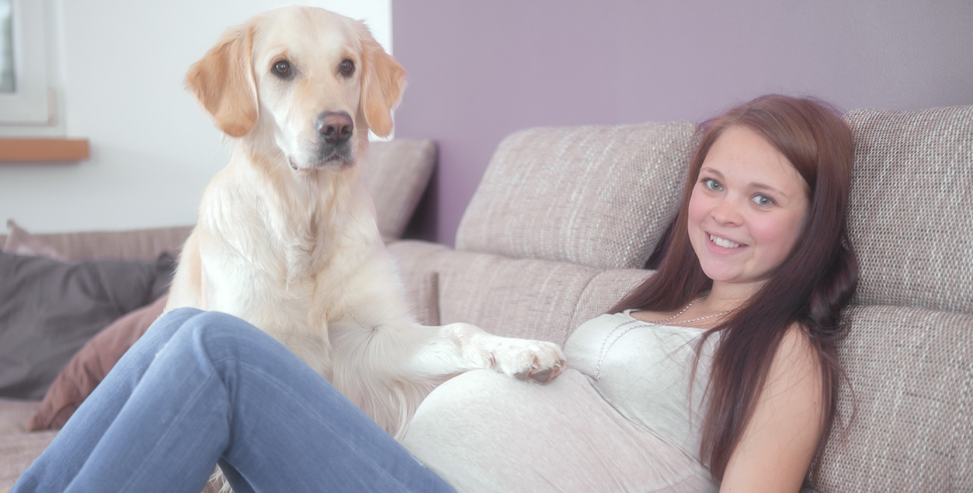 Pregnant youth reclining on sofa with dog