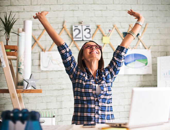 Person in an office throwing hands up in the air in excitement
