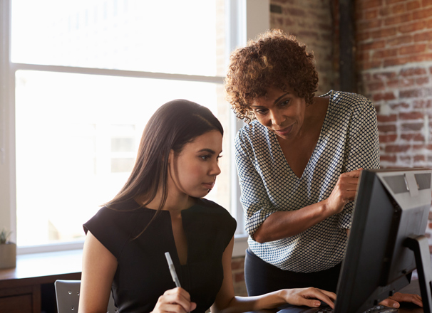Youth and adult discussion in an office with computer
