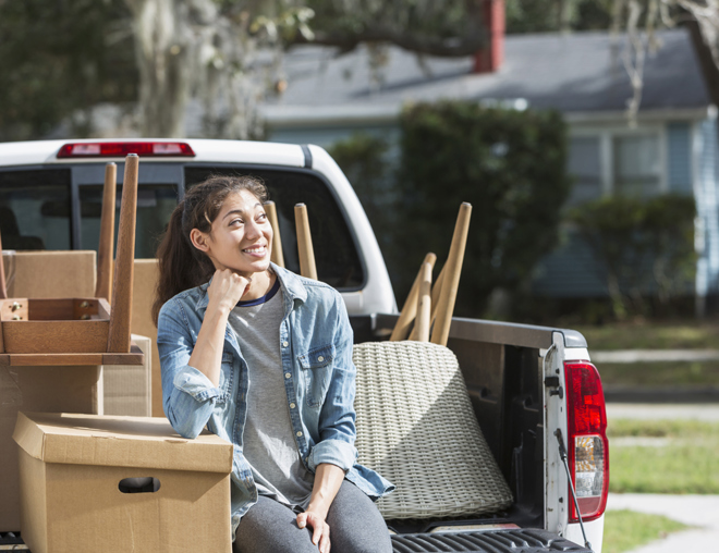 Youth sitting on the bed of a pickup truck full of furniture