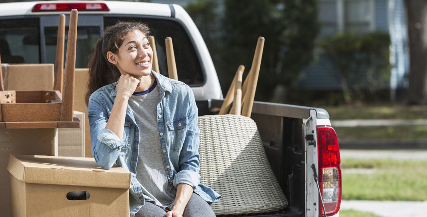 Youth sitting on the bed of a pickup truck full of furniture