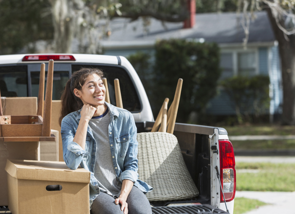Youth sitting on the bed of a pickup truck full of furniture
