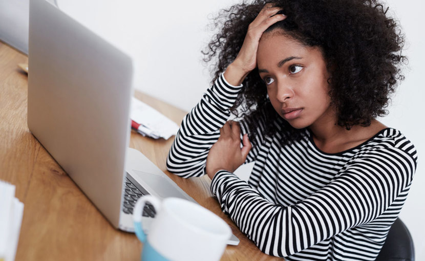 Frustrated person holding head in hand looking at computer